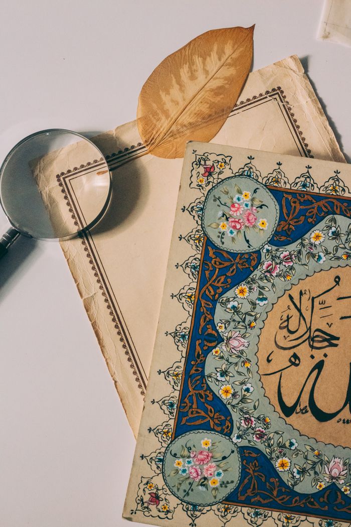 Elegant flat lay with Arabic calligraphy and magnifying glass on vintage paper.