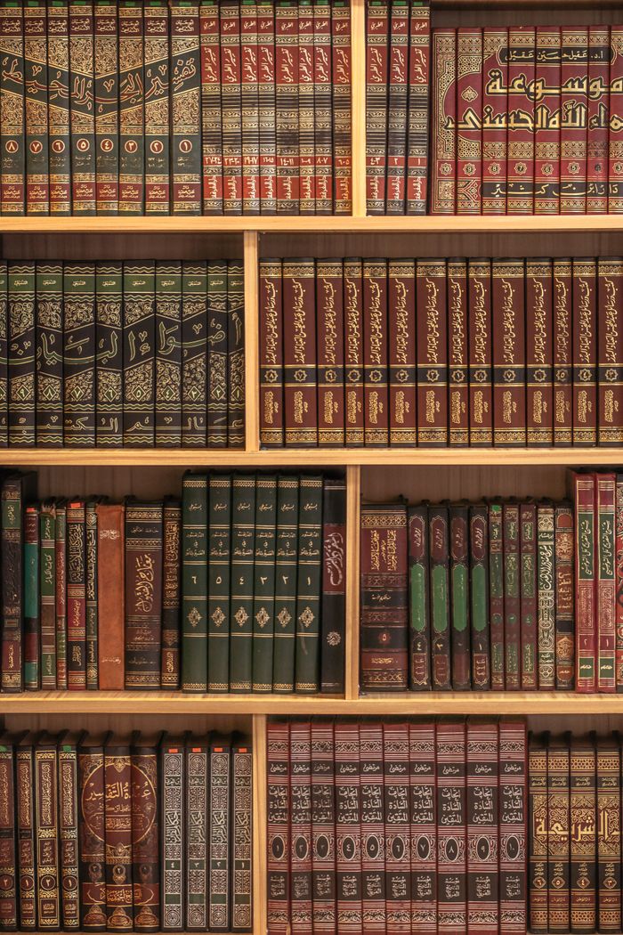 journey-01 A collection of Islamic books neatly arranged on wooden shelves showcasing rich cultural heritage.