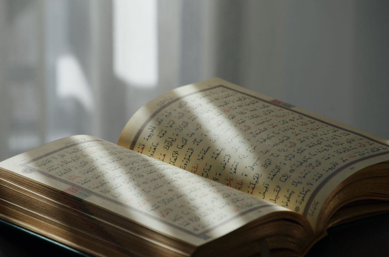 An open Quran with Arabic text, bathed in soft sunlight, symbolizing peace and spirituality.